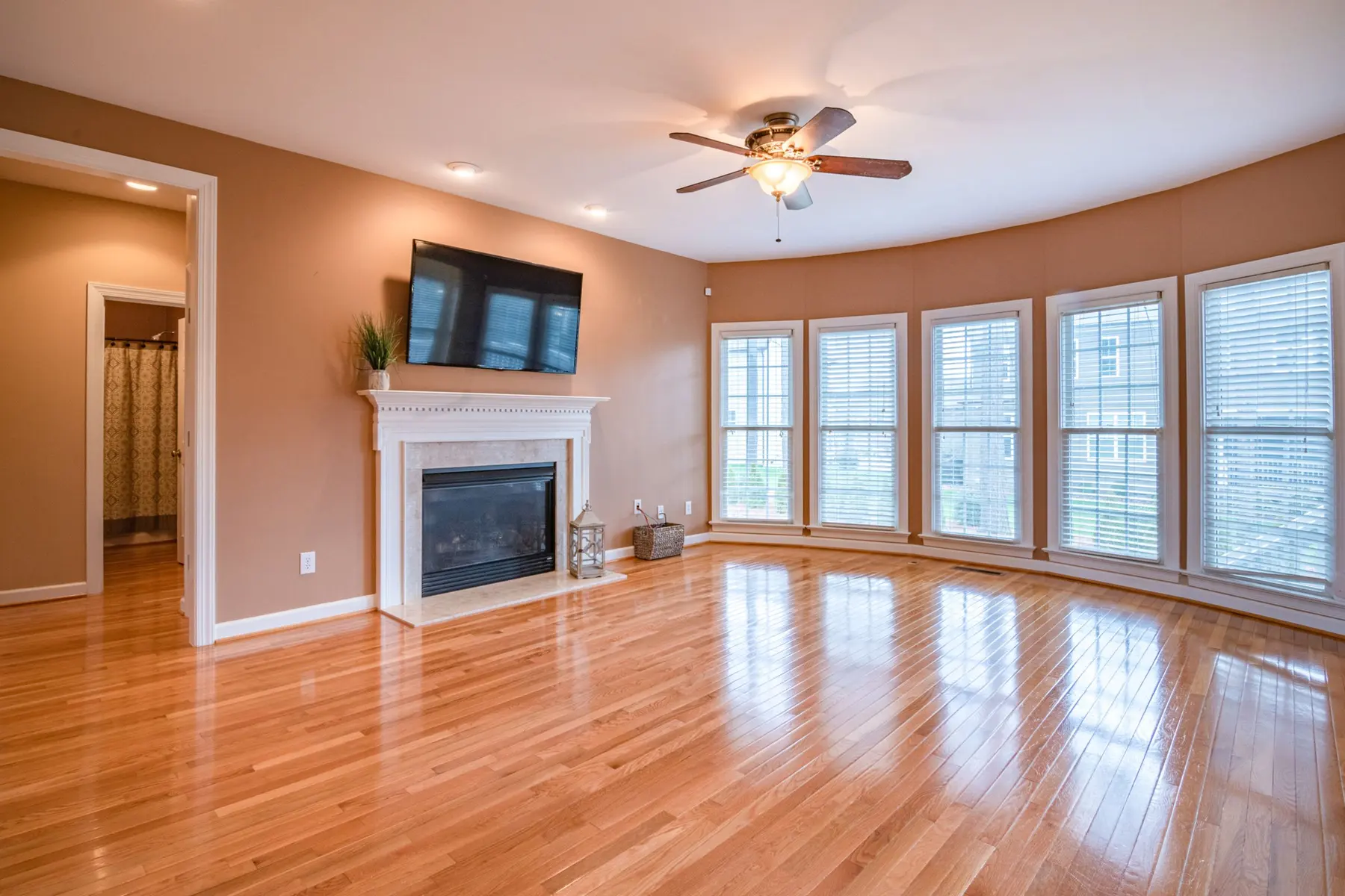 Golden oak hardwood with a high-gloss finish in a living room with a white fireplace and bay windows