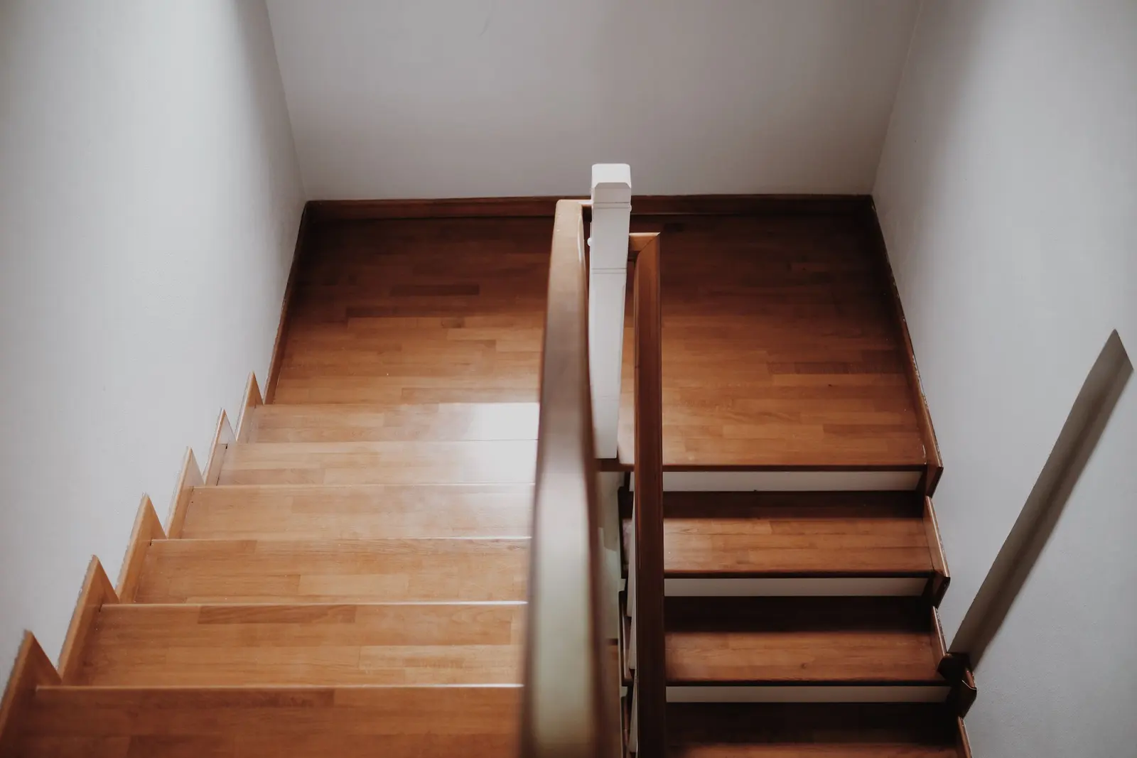 Wood staircase and landing with a stained handrail seen from the top step
